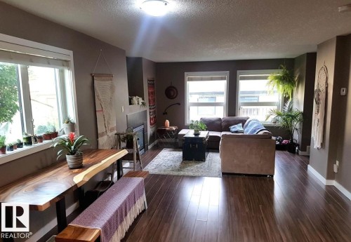 Open-concept living space featuring wood-finish flooring, multiple windows, a built-in fireplace, and neutral wall tones - 12246 103 Street, Edmonton, AB - Indoor Photo Showing Living Room
