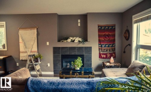 Central fireplace with dark tile surround and hearth, featuring a built-in mantel - 12246 103 Street, Edmonton, AB - Indoor Photo Showing Living Room With Fireplace