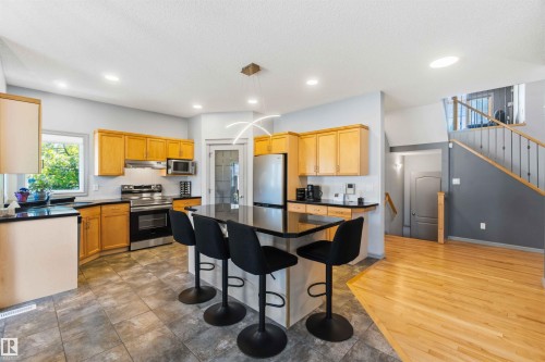 Kitchen with light wood cabinetry, dark countertops, and stainless steel appliances - 3061 Spence Wynd, Edmonton, AB 