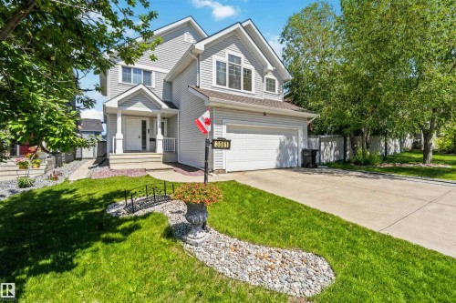 Light gray siding exterior with a prominent attached garage and concrete driveway - 3061 Spence Wynd, Edmonton, AB 