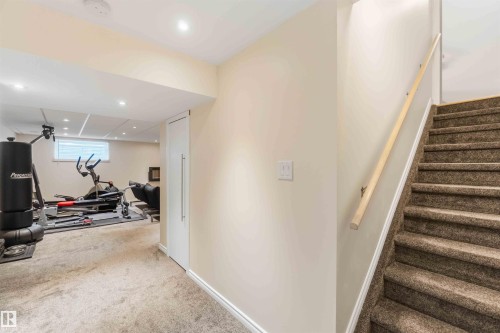 Carpeted staircase with a wood handrail leading to a lower level featuring recessed lighting, a window with blinds, and light-colored walls - 3061 Spence Wynd, Edmonton, AB 