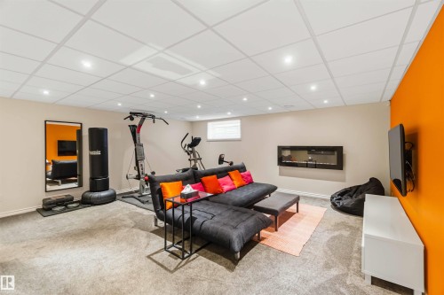 Finished basement space featuring recessed lighting, a modern wall-mounted fireplace, and light-colored carpeting - 3061 Spence Wynd, Edmonton, AB 