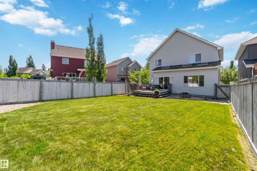 Expansive rear yard featuring a wooden privacy fence, a manicured lawn, and a multi-level wooden deck - 3061 Spence Wynd, Edmonton, AB 