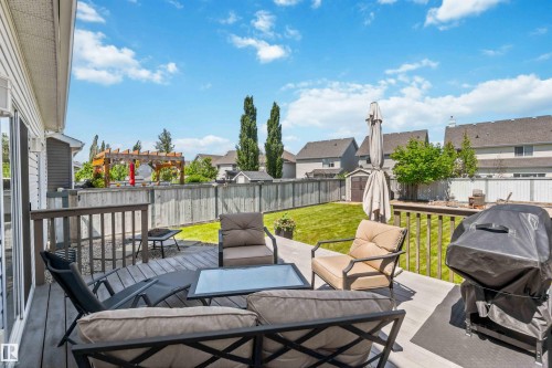 Expansive outdoor living area featuring a multi-level composite deck with railing, a manicured lawn, and a wood privacy fence - 3061 Spence Wynd, Edmonton, AB 