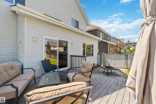 Hardwood deck with sliding glass patio door, exterior wall lighting fixtures, and a gravel area with stepping stones - 3061 Spence Wynd, Edmonton, AB 