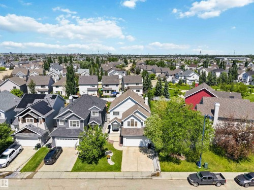 Suburban residential street featuring multiple two-story homes with attached garages, paved driveways, and manicured lawns - 3061 Spence Wynd, Edmonton, AB 