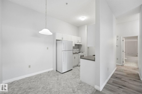 Bright kitchen area featuring white cabinetry and appliances - 105 11446 40 Avenue Nw, Edmonton, AB 