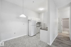 Bright kitchen area featuring white cabinetry and appliances - 