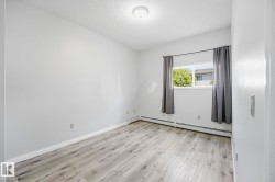 Bright room featuring wood-finish flooring, a window with exterior scenery, and white baseboards - 