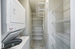 Laundry area featuring a stacked washer and dryer unit, hexagonal tile flooring, and multiple wire shelving units - 