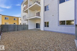 Gravel outdoor patio area featuring a wooden privacy fence, a ground-level deck, and sliding patio doors - 