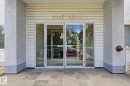 Glass entry doors with aluminum frames, stone tile flooring, stucco exterior, and horizontal vinyl siding - 105 11446 40 Avenue Nw, Edmonton, AB 