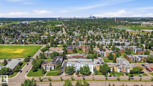 Expansive aerial showcasing a verdant residential area with a prominent city skyline visible in the distance - 105 11446 40 Avenue Nw, Edmonton, AB 