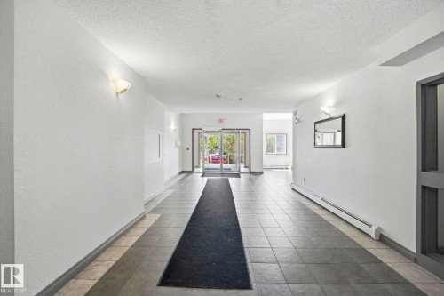 Entryway featuring geometric tile flooring, wall sconce lighting, and glass double doors - 105 11446 40 Avenue Nw, Edmonton, AB 