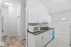 Kitchen area featuring white cabinetry, a double basin sink, and a dishwasher - 