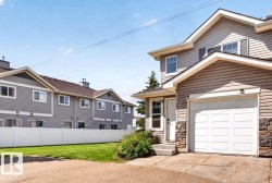 Two-story residence featuring light beige siding, a white garage door, and stone facade accents - 