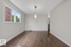 Spacious room featuring wood-finish flooring and a modern linear pendant light fixture - 
