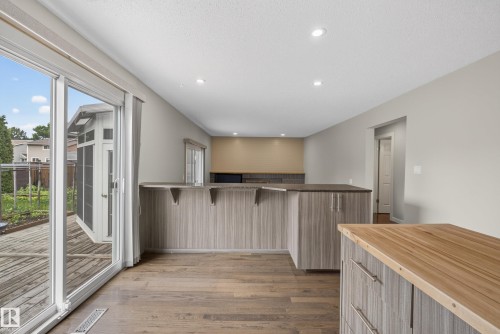 Spacious interior featuring wood-finish flooring, recessed lighting, and light-toned walls - 2712 104 Street, Edmonton, AB 