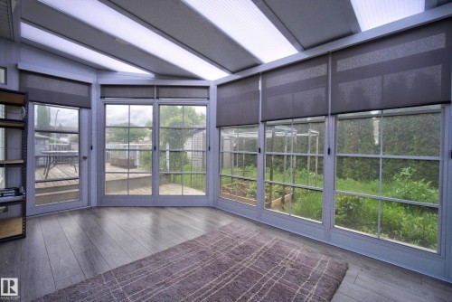 Sunroom featuring wood-finish flooring, multiple window panels, and translucent ceiling panels - 2712 104 Street, Edmonton, AB 