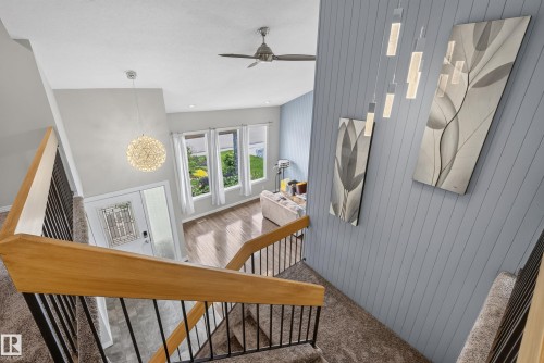 Multi-level interior featuring a contemporary staircase with wood handrails and black metal balusters - 2712 104 Street, Edmonton, AB 