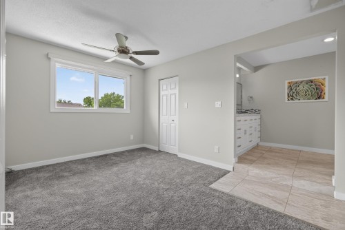 Spacious room with plush gray carpeting, a large window, and a ceiling fan - 2712 104 Street, Edmonton, AB 