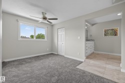 Spacious room with plush gray carpeting, a large window, and a ceiling fan - 