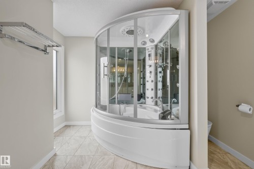 Corner shower enclosure featuring a built-in tub, multiple body jets, and overhead rainfall shower - 2712 104 Street, Edmonton, AB 