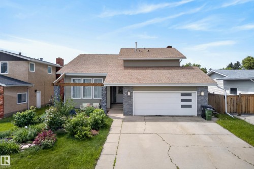 Single-family residence featuring a split-level roofline, green siding, and a stone facade - 2712 104 Street, Edmonton, AB 
