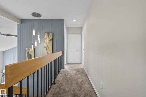 Upper-level hallway featuring plush carpeting, light gray wall finishes, and white bi-fold closet doors - 2712 104 Street, Edmonton, AB 