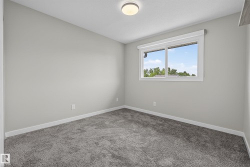 Neutral tone walls with white trim, gray plush carpet, and a window featuring white blinds - 2712 104 Street, Edmonton, AB 