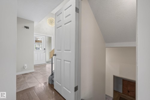 Entryway featuring a decorative frosted glass front door, a modern spherical pendant light fixture, and a combination of tile and wood-finish flooring - 2712 104 Street, Edmonton, AB 
