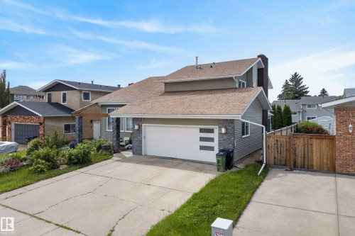 Front exterior showcasing a dual garage door with frosted glass inserts, a paved driveway, and stone veneer accents - 2712 104 Street, Edmonton, AB 