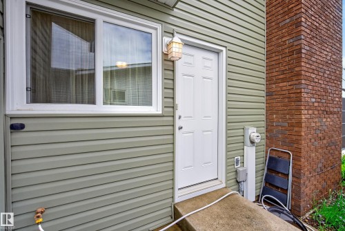 Exterior wall featuring light green horizontal siding and a red brick column - 2712 104 Street, Edmonton, AB 