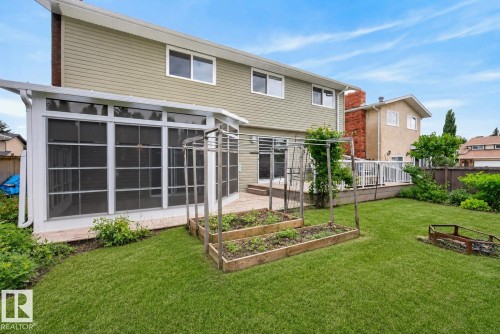 Expansive backyard with a sunroom addition, green siding, and a wood deck - 2712 104 Street, Edmonton, AB 