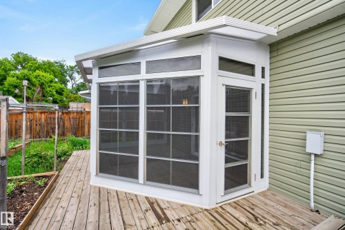 Screened outdoor room with an attached wooden deck, light green siding, and a fenced yard - 2712 104 Street, Edmonton, AB 