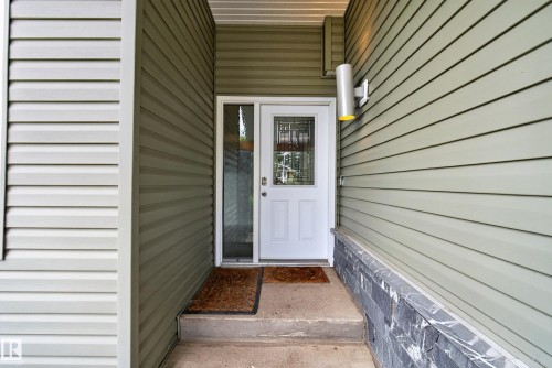 Entryway featuring light green horizontal siding and a white door with decorative glass inserts - 2712 104 Street, Edmonton, AB 