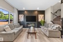 Living area featuring light wood-finish flooring and a contemporary fireplace with a geometric surround - 2146 Koshal Way, Edmonton, AB 