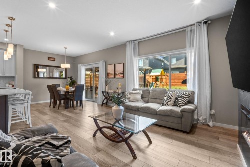 Open concept living space featuring wood-finish flooring, recessed lighting, and a linear electric fireplace - 2146 Koshal Way, Edmonton, AB 