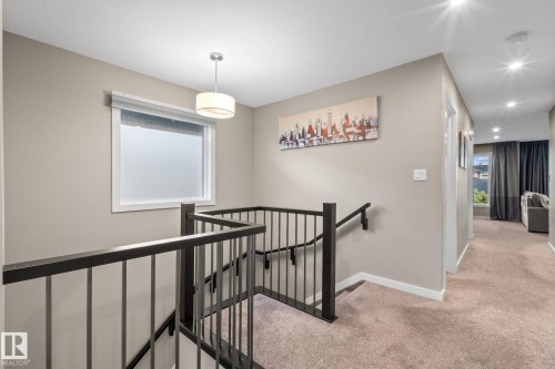 Stairwell featuring contemporary black metal railings, a white framed window, and a drum pendant light fixture - 2146 Koshal Way, Edmonton, AB 