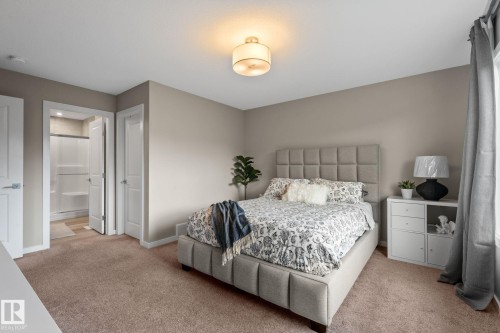 Neutral-toned bedroom featuring plush carpet flooring and a ceiling-mounted light fixture - 2146 Koshal Way, Edmonton, AB 