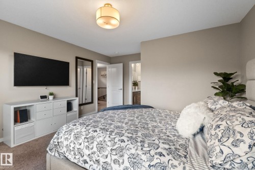 Carpeted room featuring neutral wall tones, a modern ceiling light fixture, and a built-in media console with open shelving and drawers - 2146 Koshal Way, Edmonton, AB 