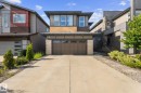 Modern two-story residence featuring a brown garage door, stone accents on the facade, and multiple upper-level windows - 2146 Koshal Way, Edmonton, AB 