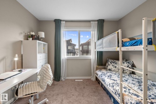 Neutral-toned room featuring a large window, carpet flooring, a built-in white storage unit, and a window with white trim - 2146 Koshal Way, Edmonton, AB 
