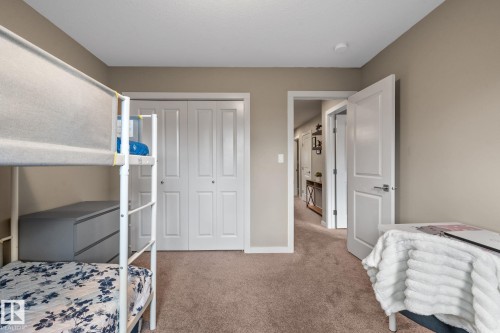 Room featuring neutral-toned walls, plush carpeting, a white bi-fold closet door, and a white interior door with brushed nickel hardware - 2146 Koshal Way, Edmonton, AB 