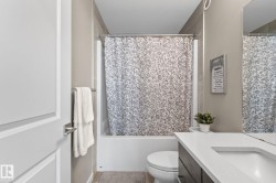 Bathroom featuring a built-in tub with a tile surround, a toilet, and a vanity with an integrated sink and countertop - 