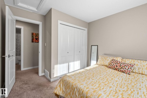 Carpeted bedroom featuring neutral wall tones, white bi-fold closet doors, and white trim - 2146 Koshal Way, Edmonton, AB 
