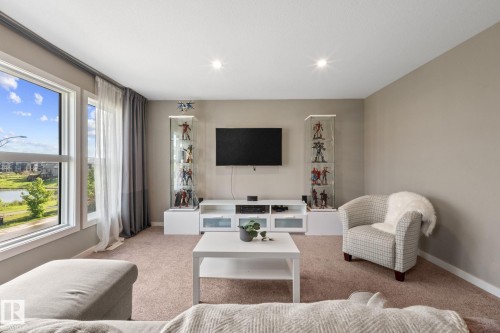 Bright living area featuring large windows, neutral wall tones, recessed lighting, and carpet flooring - 2146 Koshal Way, Edmonton, AB 