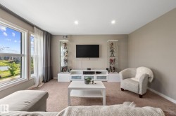 Bright living area featuring large windows, neutral wall tones, recessed lighting, and carpet flooring - 