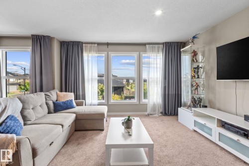 Living area featuring a wall of four windows, recessed ceiling lighting, and neutral-toned carpeting - 2146 Koshal Way, Edmonton, AB 