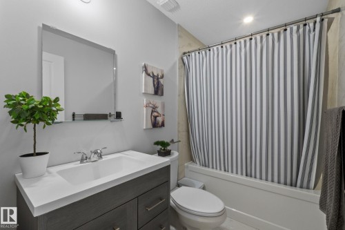 Bathroom featuring a single vanity with an integrated sink, polished chrome faucet, and a dark wood-finish cabinet - 2146 Koshal Way, Edmonton, AB 